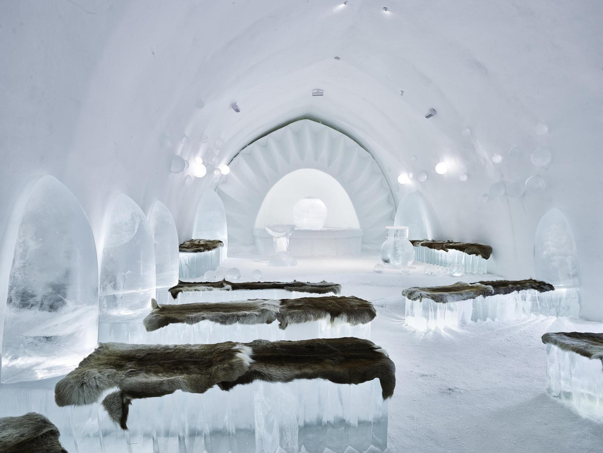 Une chapelle faite entièrement de glace avec des fourrures de rennes sur les bancs.