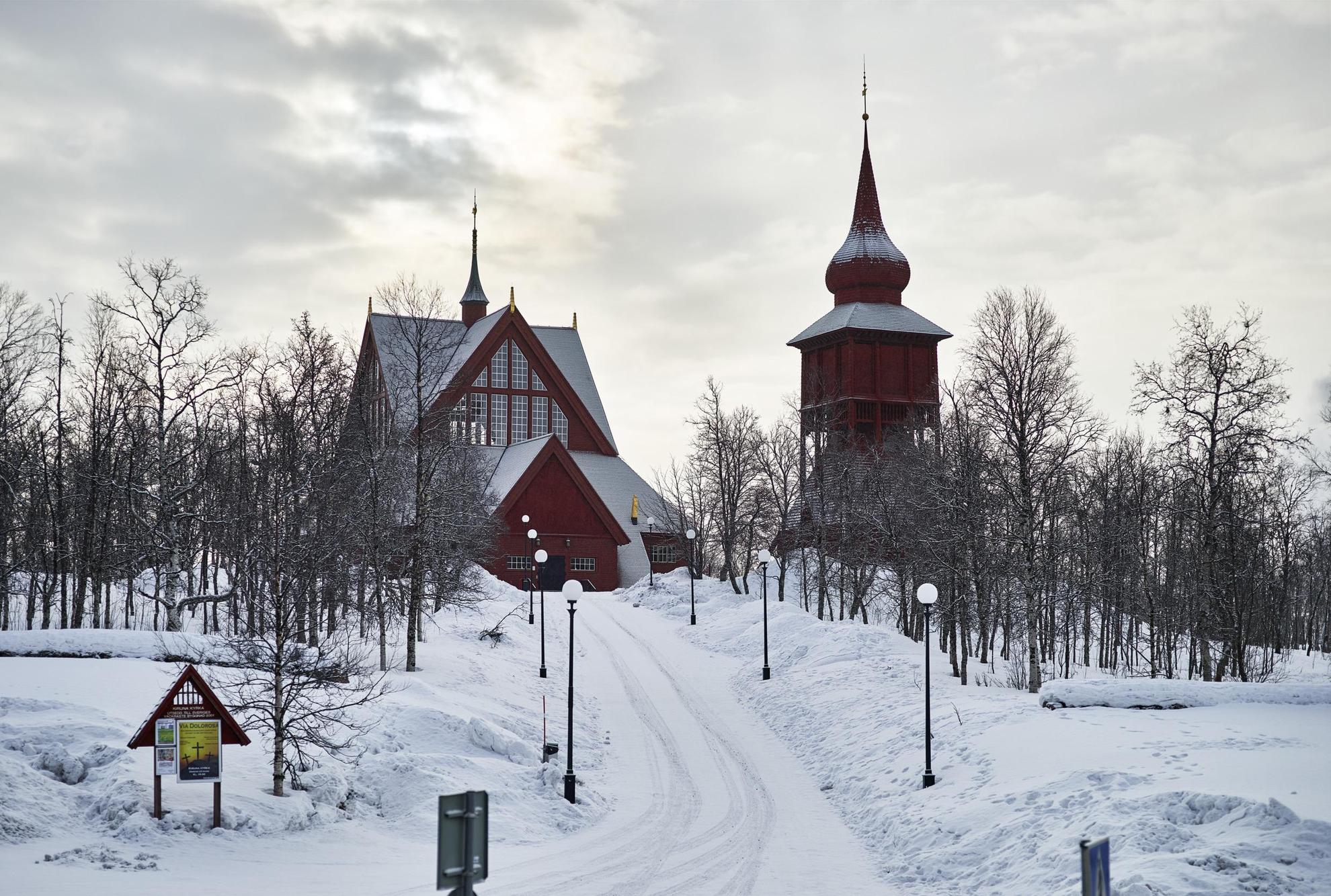 L'église de Kiruna, composé d'un bâtiment en bois avec un clocher situé à côté, se trouve sur une pente enneigée.