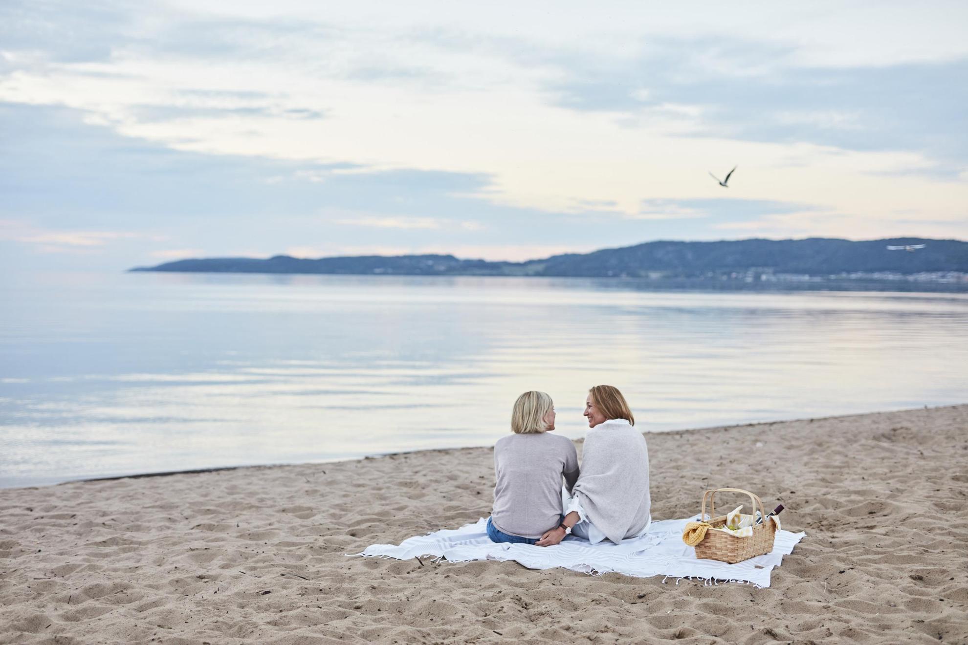Deux femmes sont assises sur une serviette sur la plage.