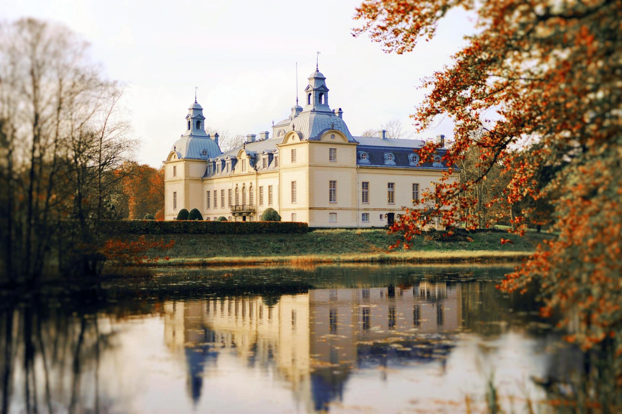 Le château de Kronovall à côté d'un lac durant l'automne. Le château se reflète sur l'eau.