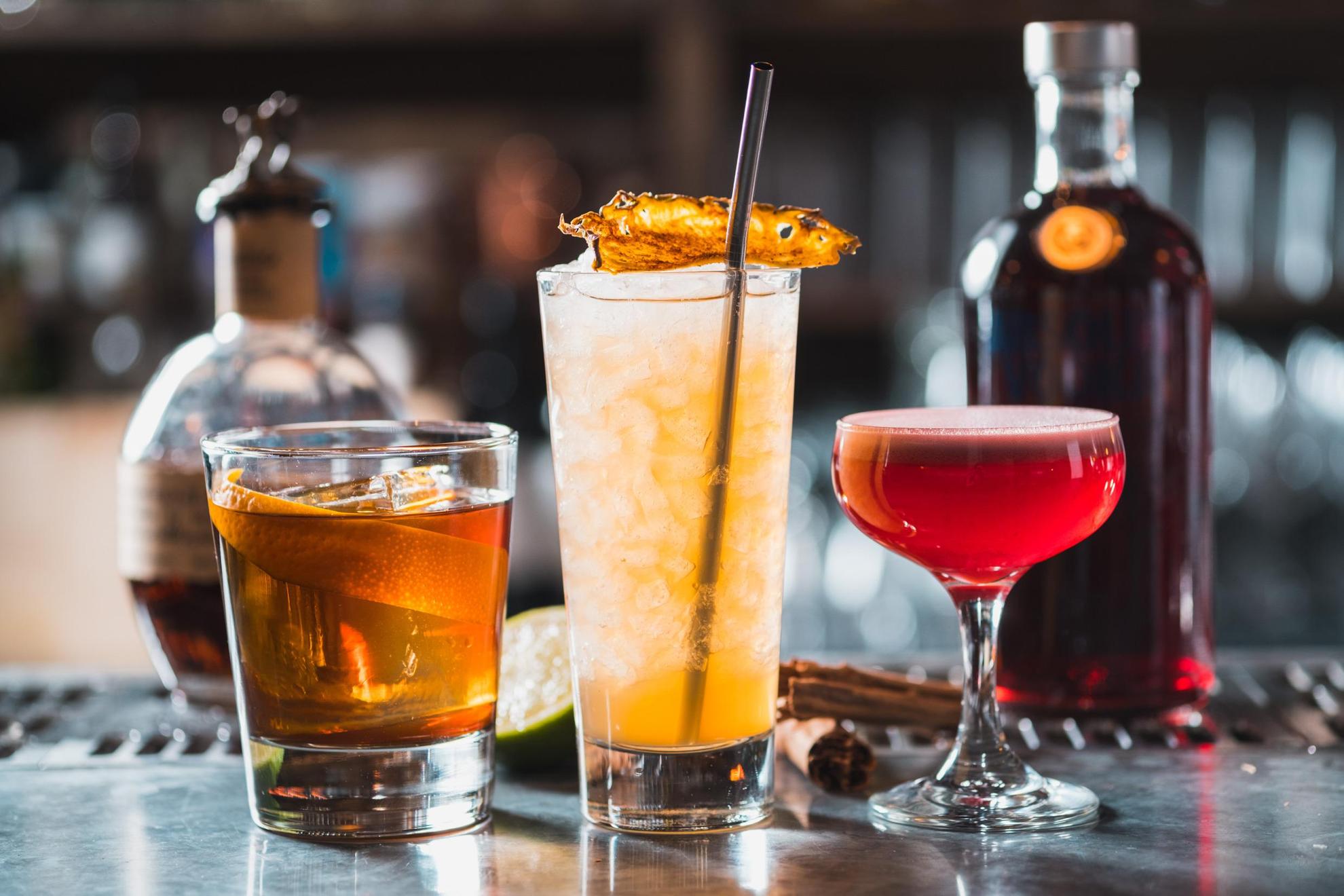 Trois cocktails différents sont posés sur un comptoir dans un bar.
