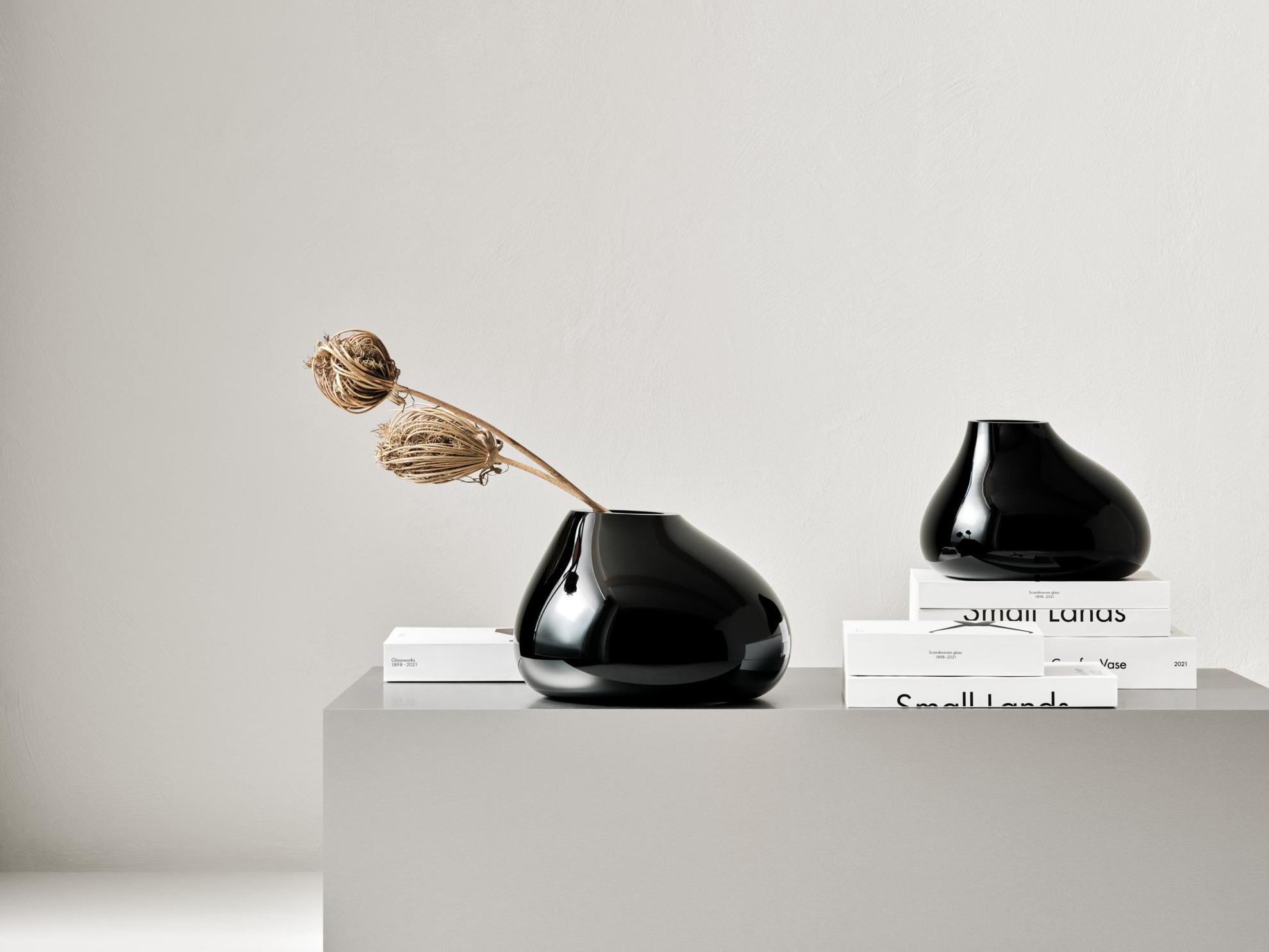 Deux vases noirs sont posés sur un meuble gris.