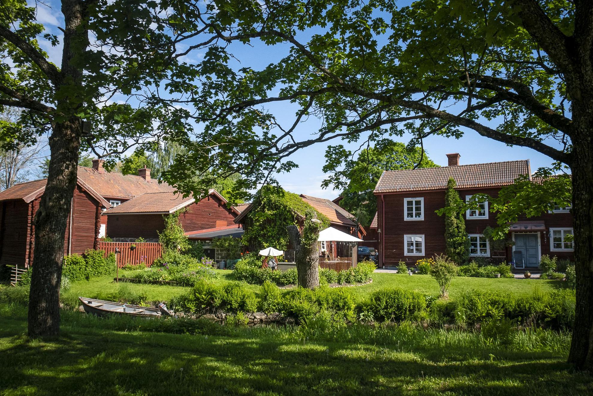 Plusieurs maisons traditionnelles peintes avec la célèbre peinture Falu Rödfärg et entourées de verdure.