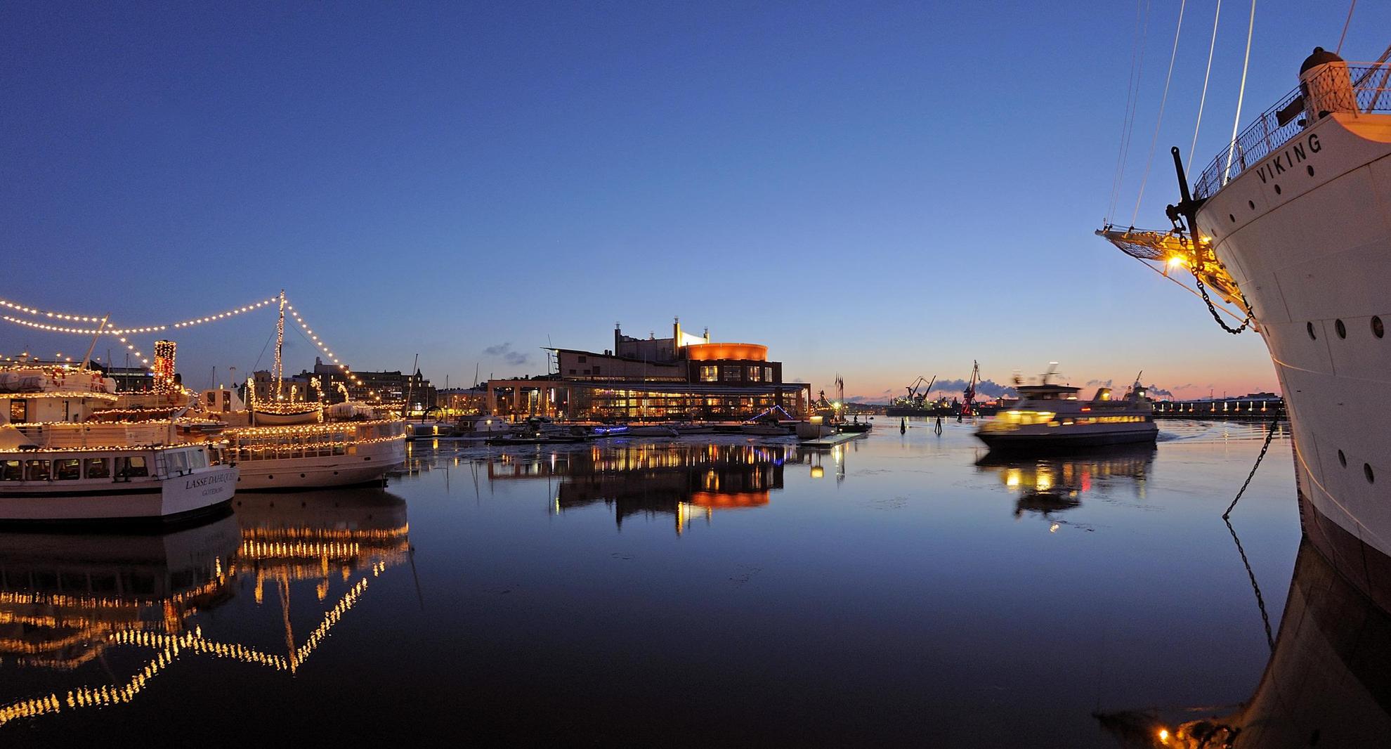 C'est le crépuscule dans le port de Göteborg où de grands bateaux avec des mâts lumineux sont amarrés.