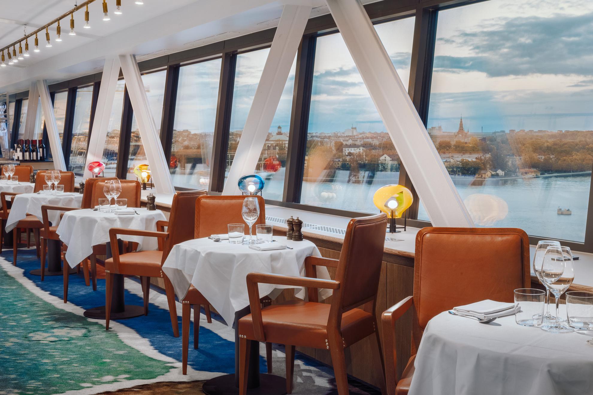 Des tables et des chaises du restaurant Gondolen avec de grandes fenêtres donnant sur l'eau.