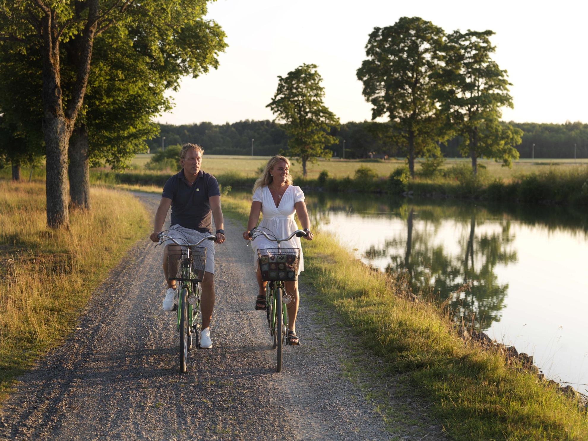 Un homme et une femme en train de faire du vélo le long du canal Göta en été.