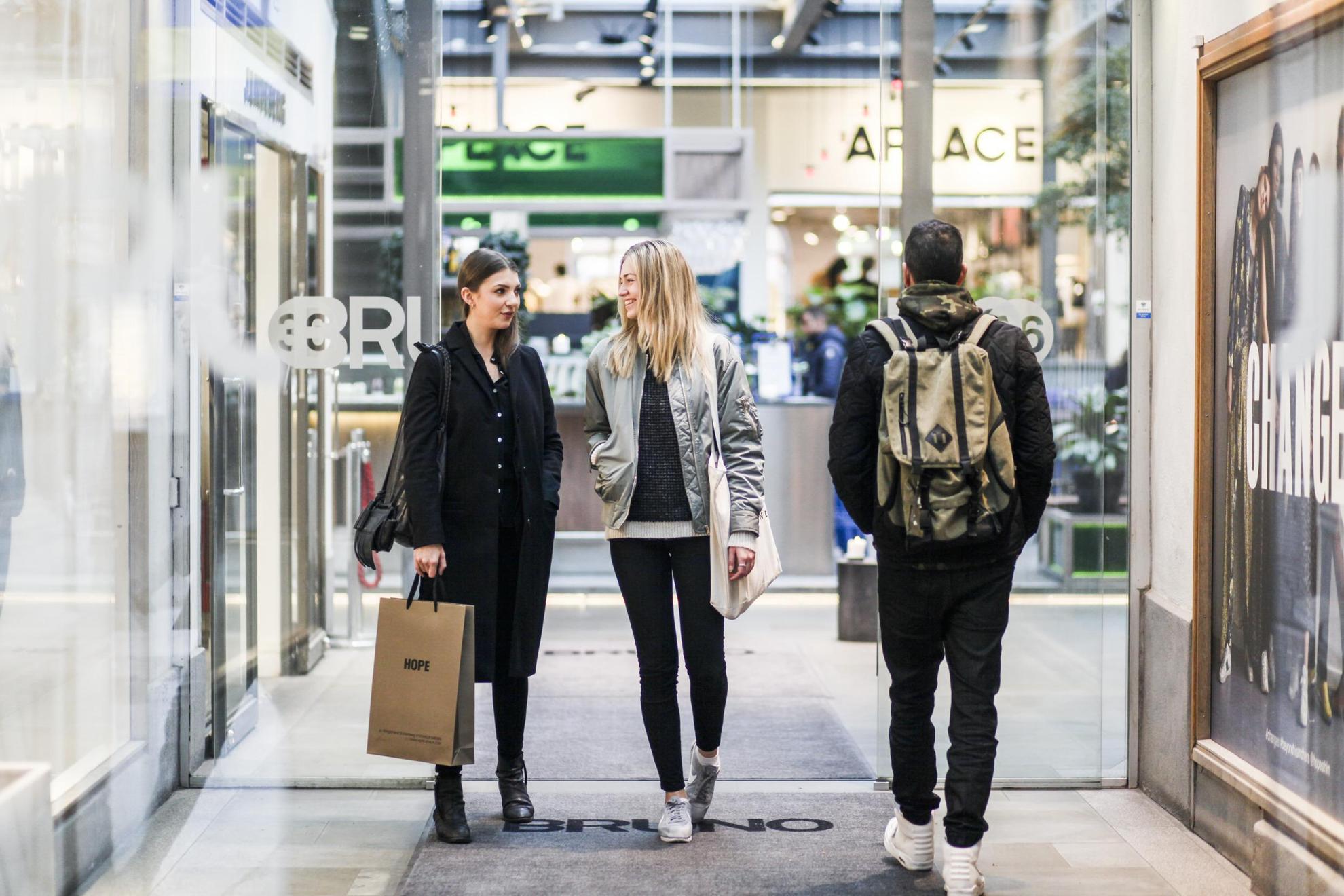 Un homme avec un sac à dos sort d'un magasin à Stockholm pendant que deux femmes y entrent.