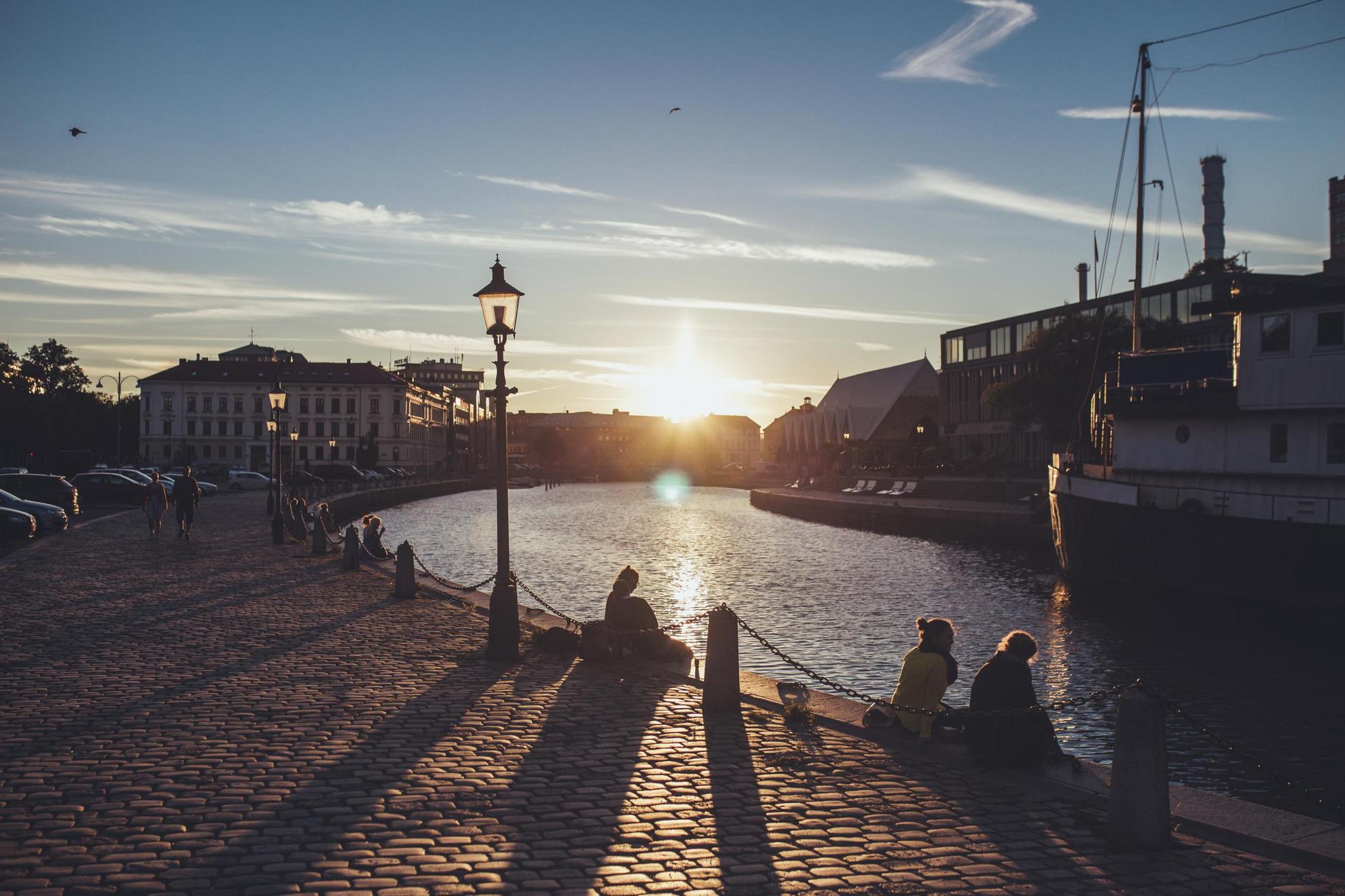 Deux personnes assises sur la jetée qui regardent le coucher du soleil à Göteborg.