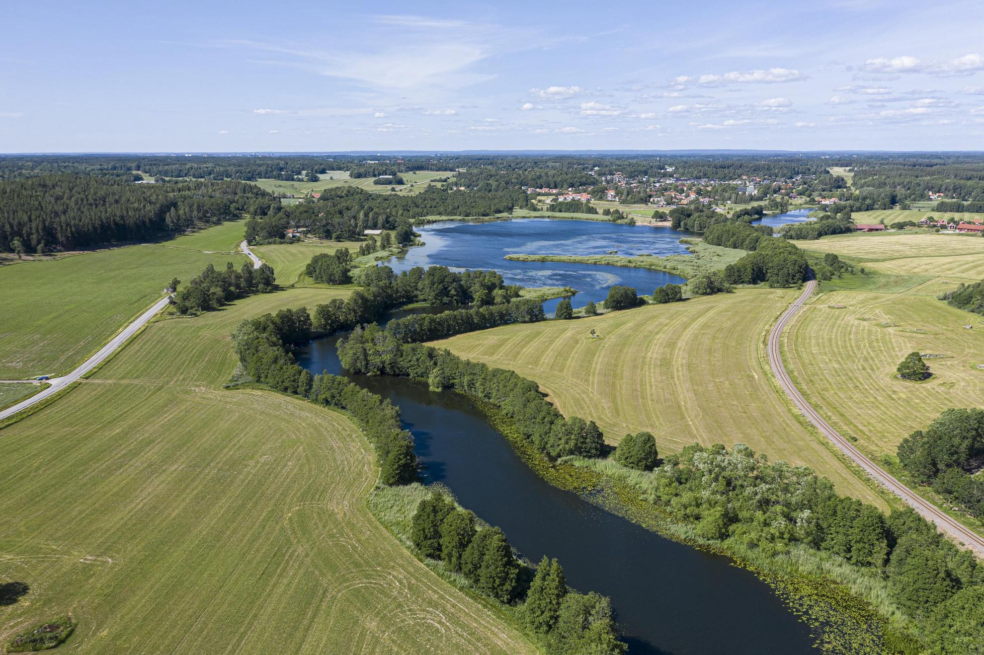 Vue aérienne d'une rivière qui serpente à travers des champs verdoyants et des arbres.