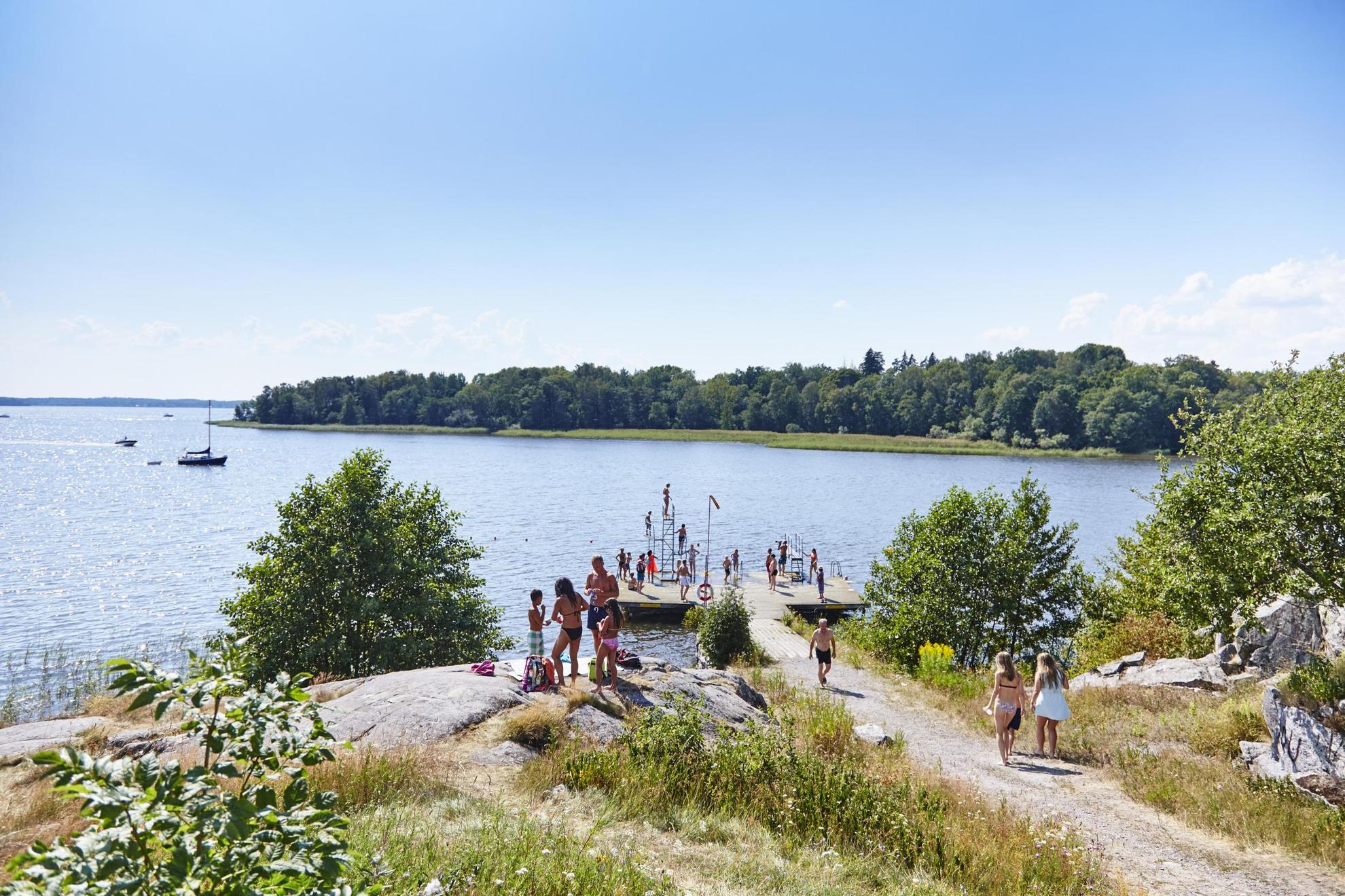 Des personnes se tiennent au bord d'un lac en été.