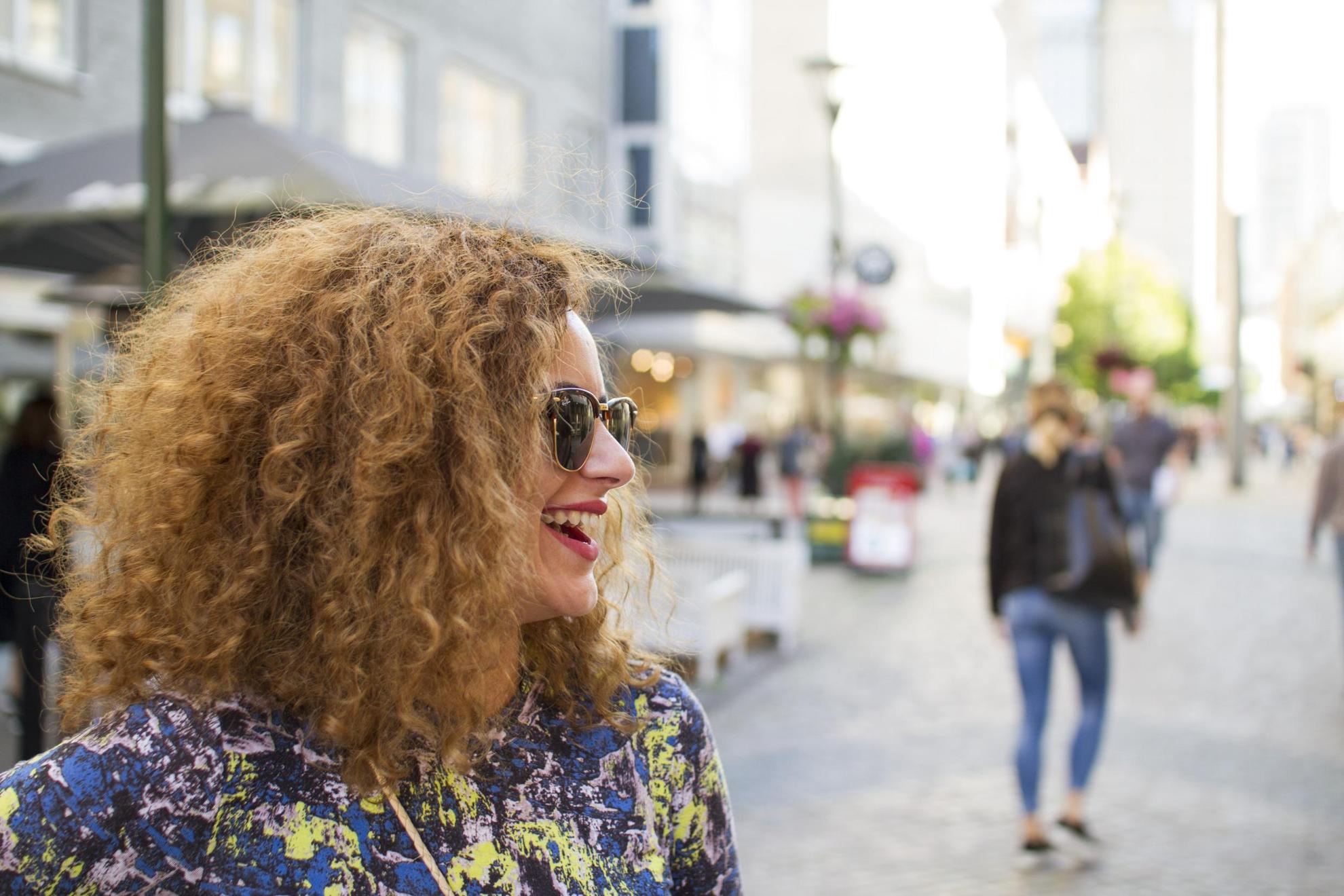Profile of a woman wearing shades standing on a pedestrian street in Malmö.