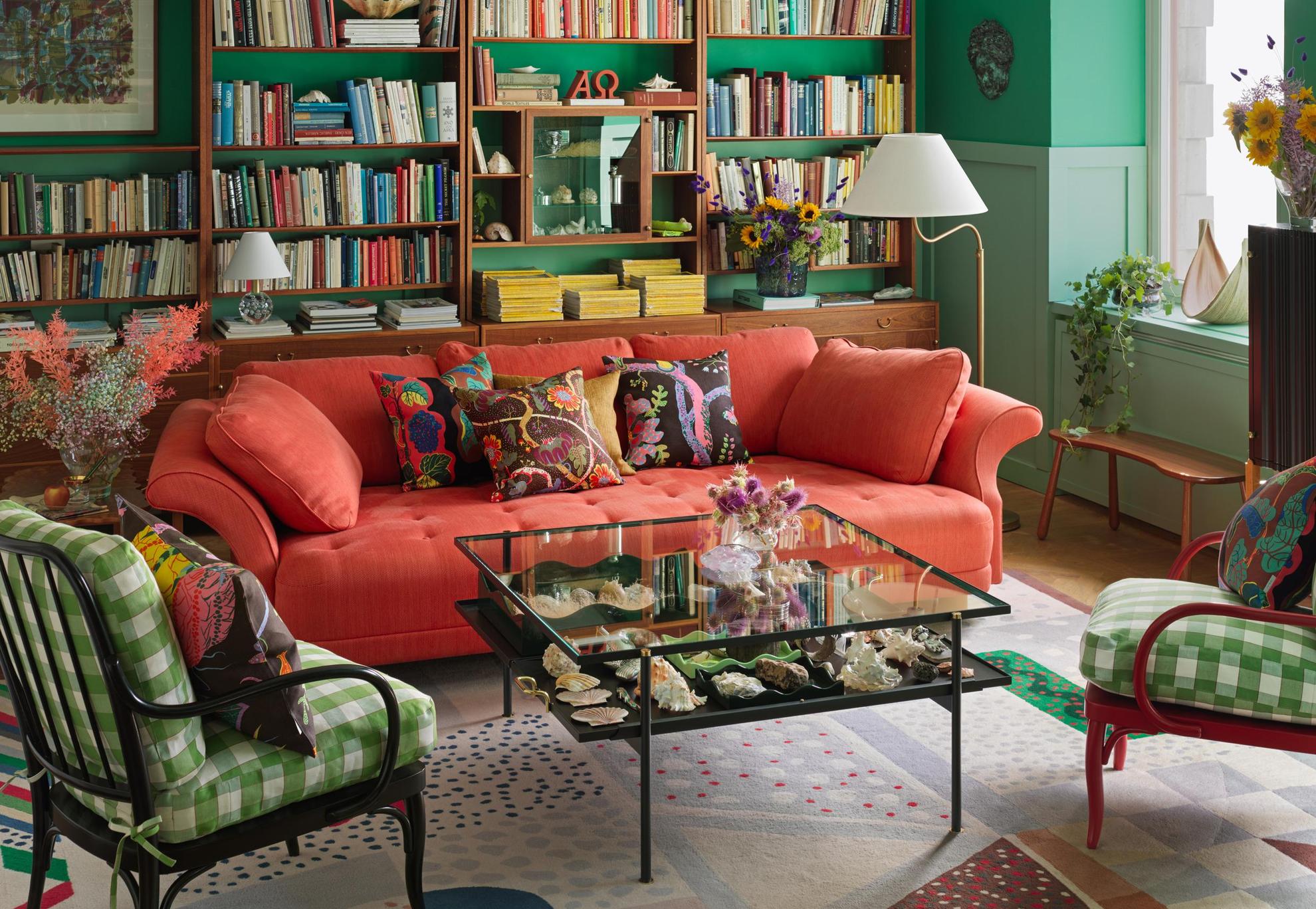 Un salon du magasin de design d'intérieur Svenskt Tenn. Une table carrée et deux fauteuils se tiennent devant un canapé rouge. Des vases, des livres, des chandeliers et d'autres objets de design d'intérieur décorent la pièce.