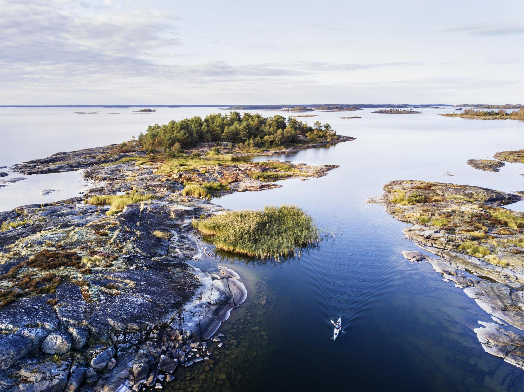 Une personne fait du kayak entre de petites îles sur le lac Vänern en été.