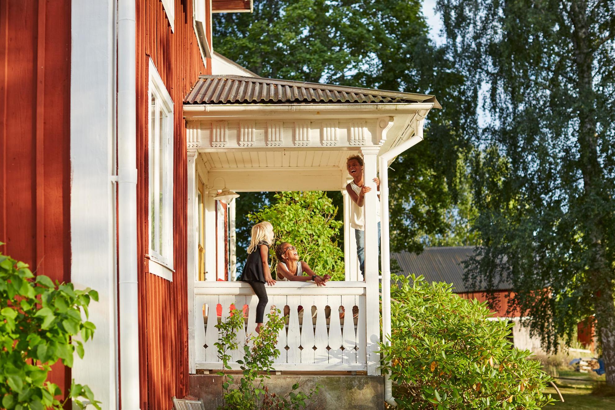 Three kids are playing on the porch of a summer house in the countryside.