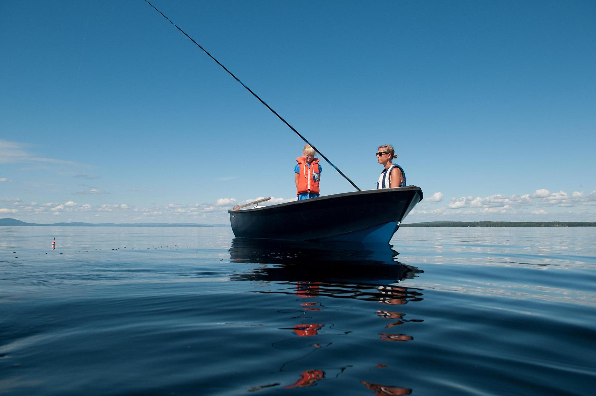 Vue sur deux personnes dans une barque en train de pêcher sur un lac.