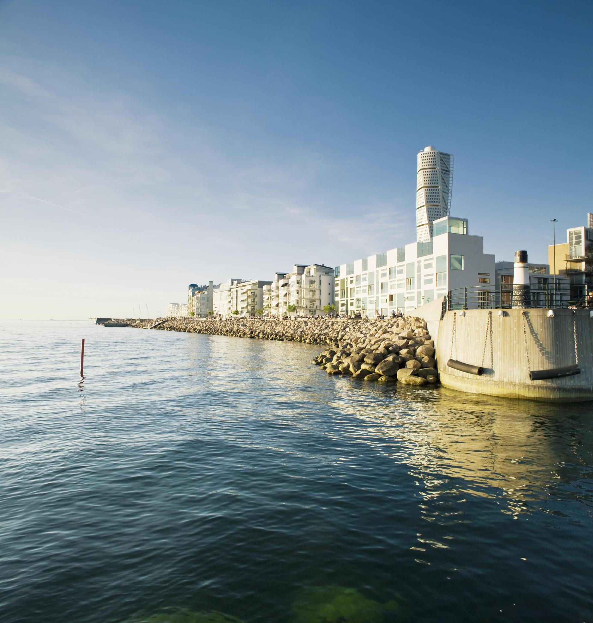 Vue sur la ville de Malmö avec notamment l'océan, une jetée en béton, des immeubles et le gratte-ciel Turning Torso.