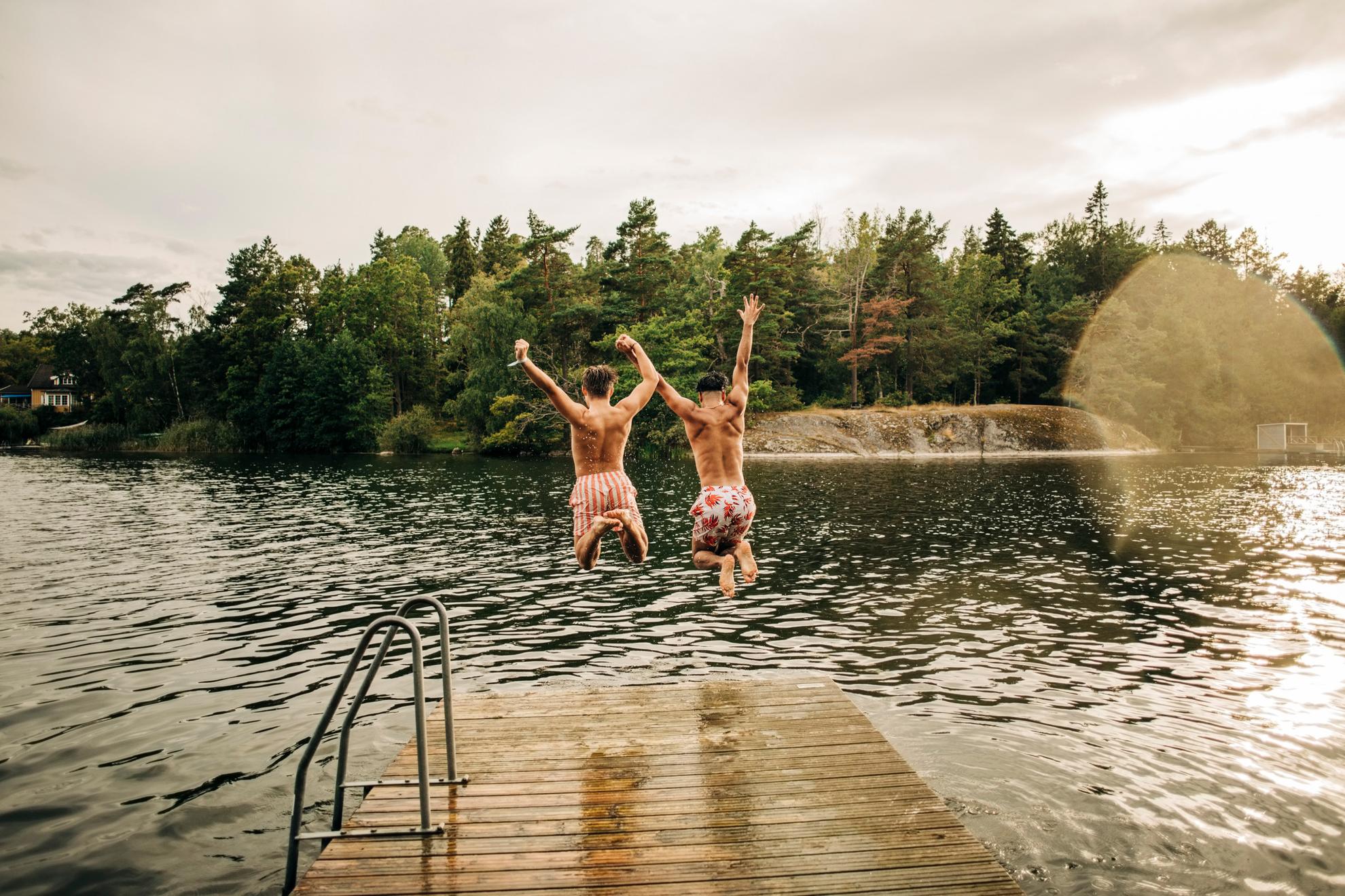 Deux hommes sautent d'une jetée dans un lac.