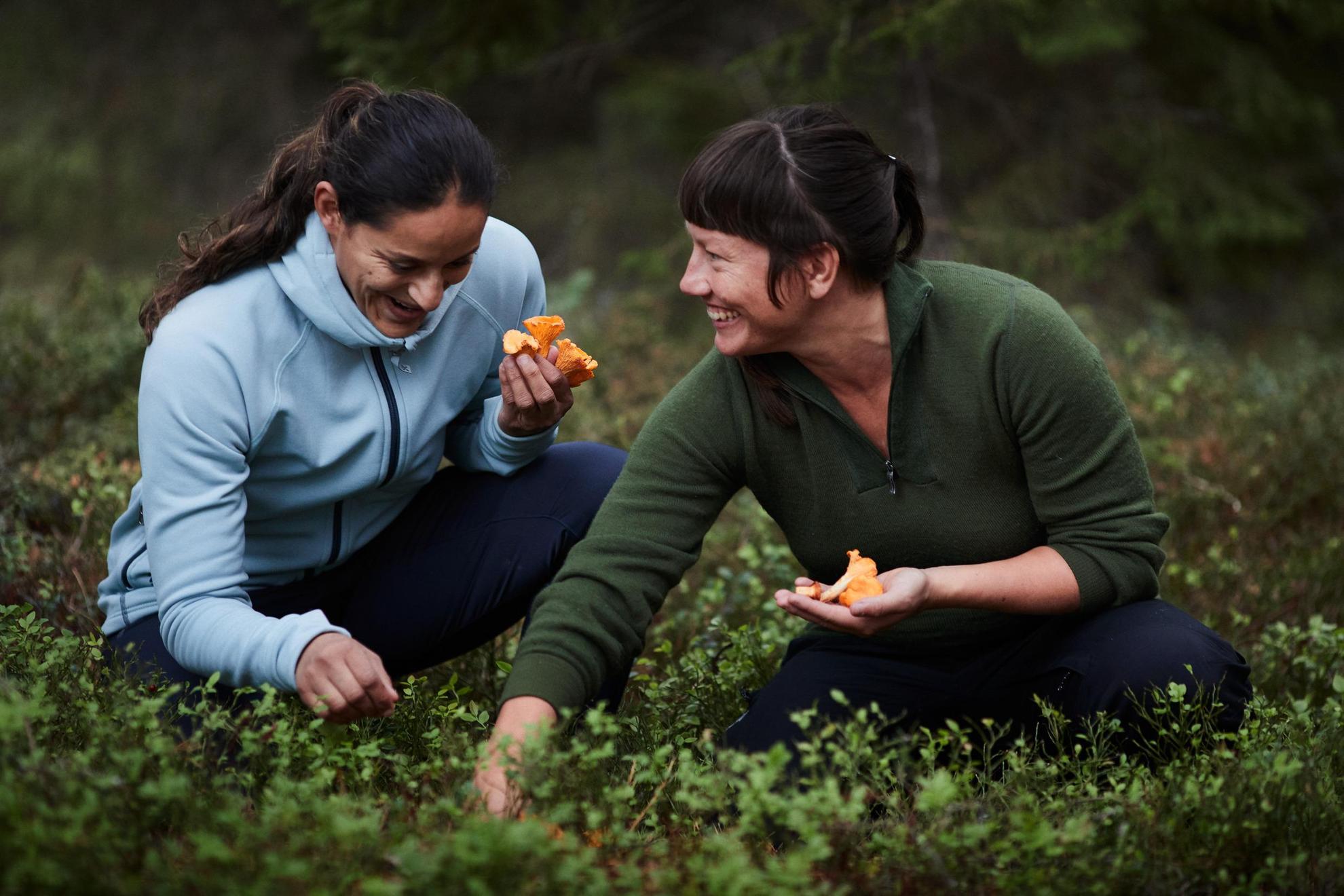 Deux femmes sont accroupies côte à côte dans la forêt en train de ramasser des champignons