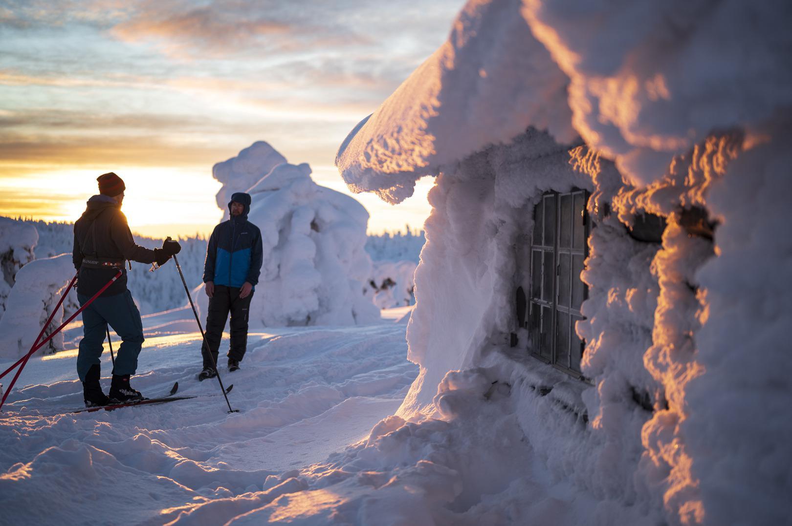 Des randonneurs à ski près d'un chalet dans un paysage d'hiver..