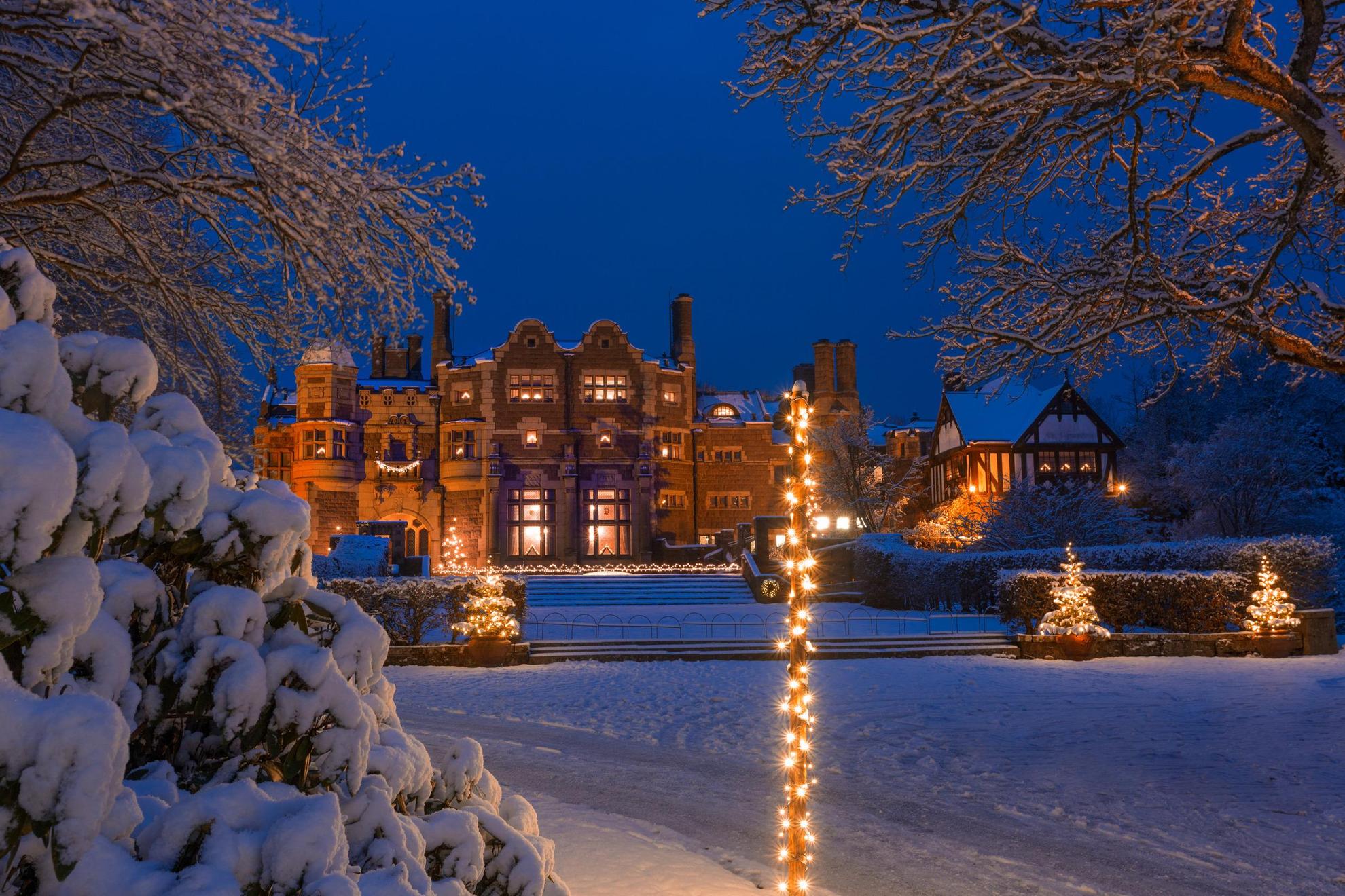 Un château recouvert de neige et de lumières de Noël à la nuit tombée.